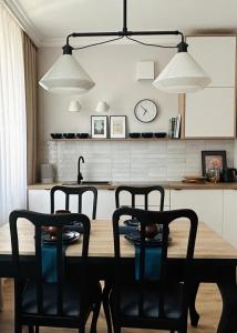 a dining room table with chairs and a clock on the wall at Apartament 101 in Piła