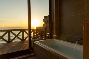 a bathroom with a tub with a view of the ocean at Nesoberi VILLA TAKASU in Kanoya