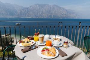 a table with plates of breakfast food on a balcony at Piccolo Hotel in Malcesine