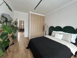 a bedroom with a large bed with a green headboard at Apartament 101 in Piła