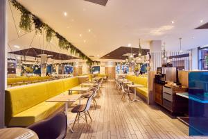 a restaurant with long tables and yellow booths at a&o Manchester City Centre in Manchester