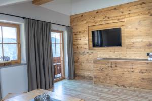 a living room with a television on a wooden wall at Bio Alpenhof Rostatt in Bischofshofen