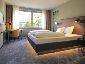 a bedroom with a bed and a desk and a window at Mercure Hotel Plaza Essen in Essen +33 photos