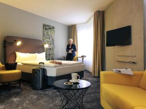 a woman is standing in a hotel room at Mercure Hotel Plaza Essen in Essen