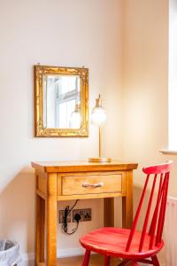 a red chair sitting next to a wooden desk with a mirror at Hilltop Views by Escape Ordinary in Killyhevlin +50 photos