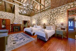 a bedroom with two beds and a stone wall at Arniston Hotel Manor House in Arniston +43 photos