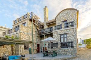 a large stone building with a table and an umbrella at Arniston Hotel Manor House in Arniston