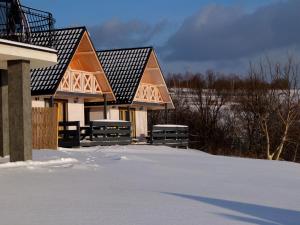 a pair of houses in the snow with snow covered ground at Apartamenty Żywiec in Żywiec