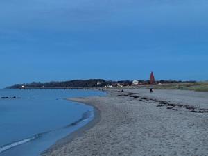a beach with people walking on the sand and water at Ferienwohnung und Ferienzimmer in Neubukow