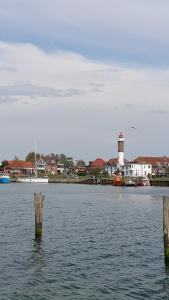 two posts in the water with a lighthouse in the background at Ferienwohnung und Ferienzimmer in Neubukow
