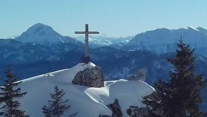 ein Kreuz auf einem schneebedeckten Berggipfel in der Unterkunft Bocksleitnerhof in Wackersberg