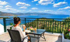 a woman sitting at a table on a balcony looking at the ocean at Istron Homes in Istro