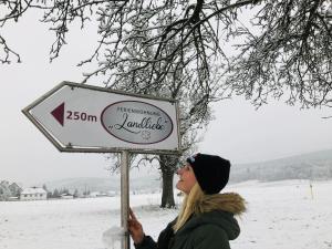 a woman standing next to a sign in the snow at Ferienwohnungen Landliebe "Auszeit mit Wohlgefühl" in Catharinau +55 photos