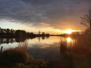 a sunset over a lake with the sun setting at Ferienwohnung Alte Dorfschule in Lüssow +22 photos