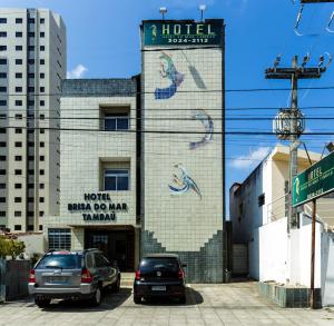 若昂佩索阿的住宿－Hotel Brisa do Mar Tambaú，两辆车停在大楼前的建筑物