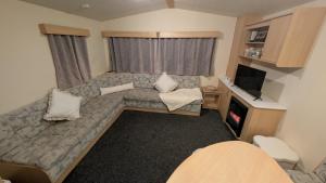 a small living room with a couch and a tv at Shore&Meadow Holiday Lets - Luxury 8 berth caravan at Regent Bay in Morecambe