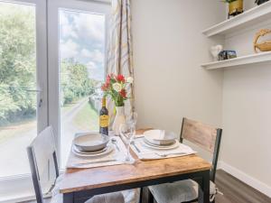 a dining table with a bottle of wine and a vase of flowers at Kingsleys Lodge in Barnstaple