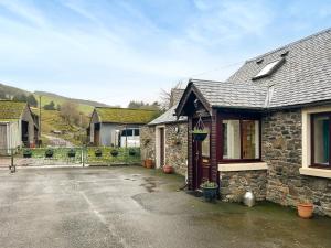 a stone house with a driveway in front of it at Bothy Cottage - Uk51350 in Peebles