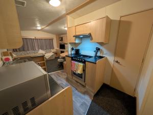 a kitchen with a stove top oven next to a living room at Shore&Meadow Holiday Lets - Luxury 8 berth caravan at Regent Bay in Morecambe