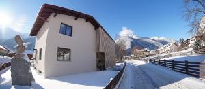 a building in the snow with mountains in the background at Der Steinadler in Umhausen