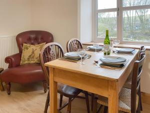 a dining room table with chairs and a bottle of wine at Smardale Cottage in Kirkby Stephen