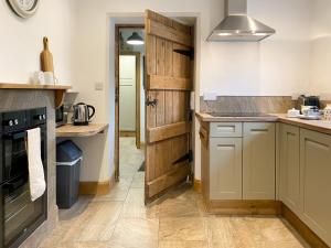 a kitchen with white cabinets and a wooden door at Smardale Cottage in Kirkby Stephen