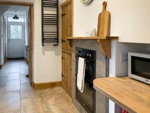 a kitchen with a stove and a counter with a microwave at Smardale Cottage in Kirkby Stephen