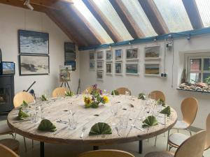 a large wooden table with glasses and flowers on it at Gulfhof Friedrichsgroden in Carolinensiel