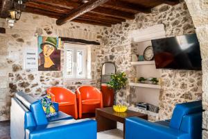 a living room with orange chairs and a tv at Art House with Seaview & Jacuzzi by Konnect in Spartýlas