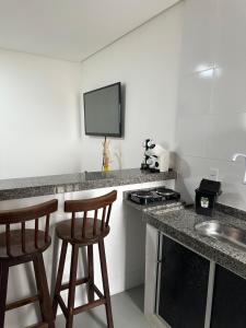 a kitchen with two bar stools and a counter top at Apartamento aconchegante em Irecê in Irecê +11 photos