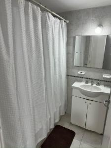 a bathroom with a white shower curtain and a sink at Altos de Centro Chivilcoy 7 in Chivilcoy