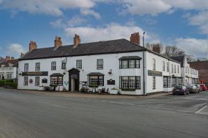 a white building on the corner of a street at The Crown Hotel, Boroughbridge, North Yorkshire - The Coaching Inn Group in Boroughbridge