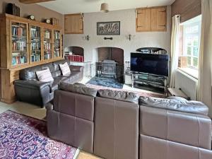 a living room with leather couches and a flat screen tv at Abbott's Farm in Horbling +22 photos