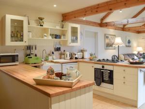a kitchen with white cabinets and a wooden counter top at Garrique Cottage in Kippen