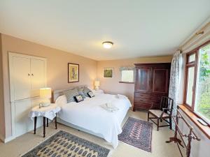 a bedroom with a large white bed and a window at Garrique Cottage in Kippen +18 photos