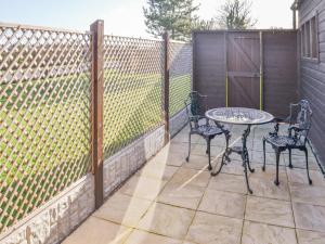 a fence with two chairs and a table on a patio at Willow Tree Farm in Sutton on Sea +3 photos