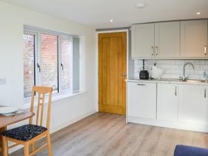 a kitchen with white cabinets and a wooden table at Willow Tree Farm in Sutton on Sea