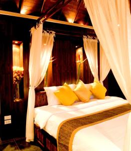 a bedroom with a bed with white and yellow pillows at Baan Thai Surin Garden in Surin Beach +17 photos