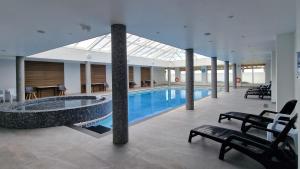 a large swimming pool in a building with chairs and a table at Widemouth Waves Holiday Chalet in Poundstock