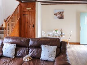 a brown leather couch with a teddy bear sitting on it at Towy Cottage - Uk49589 in Llansawel