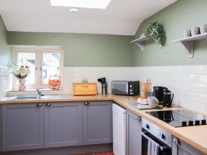 a kitchen with gray cabinets and green walls at Towy Cottage - Uk49589 in Llansawel