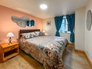 a bedroom with a bed and a window with blue curtains at Ploughman's Rest - Uk51336 in Peebles