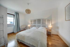 a white bedroom with a bed and two lamps at Chiemsee Ferienwohnung Gartenblick in Prien am Chiemsee