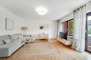 a white living room with a couch and a tv at Chiemsee Ferienwohnung Gartenblick in Prien am Chiemsee