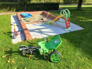 a green tricycle parked in the grass next to a playground at Haus-Auetal in Bliedersdorf