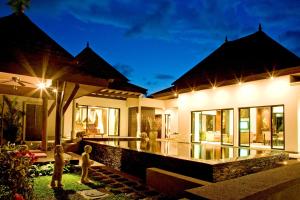 a villa with a swimming pool at night at Baan Thai Surin Garden in Surin Beach