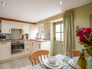 a kitchen with white cabinets and a table with chairs at Fern Cottage in Bradwell +25 photos