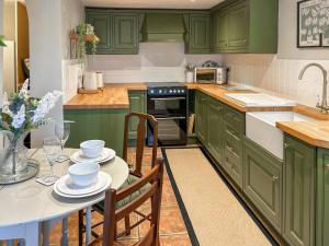 a kitchen with green cabinets and a table with chairs at River View in Lazonby