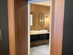 a bathroom with two sinks and two mirrors at Hôtel Le Yachtman, The Originals Collection in La Rochelle