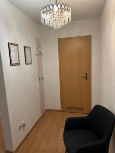 a room with a chandelier and a chair and a door at Ferienwohnung Kraus 2-4 Pers in Herbolzheim